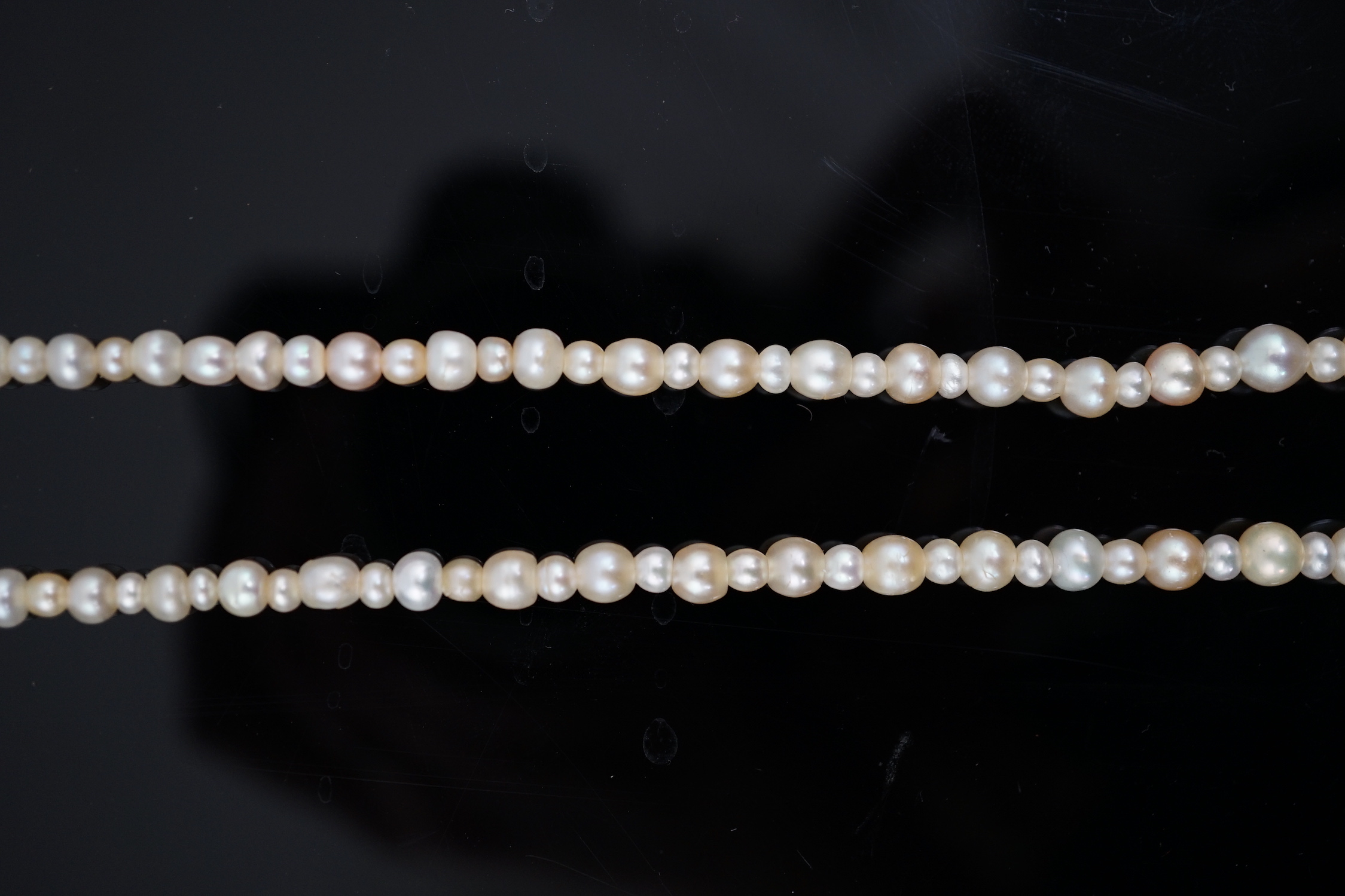 A late 19th century single strand graduated natural saltwater pearl necklace, with a French 18ct white gold and millegrain set diamond marquise shaped clasp